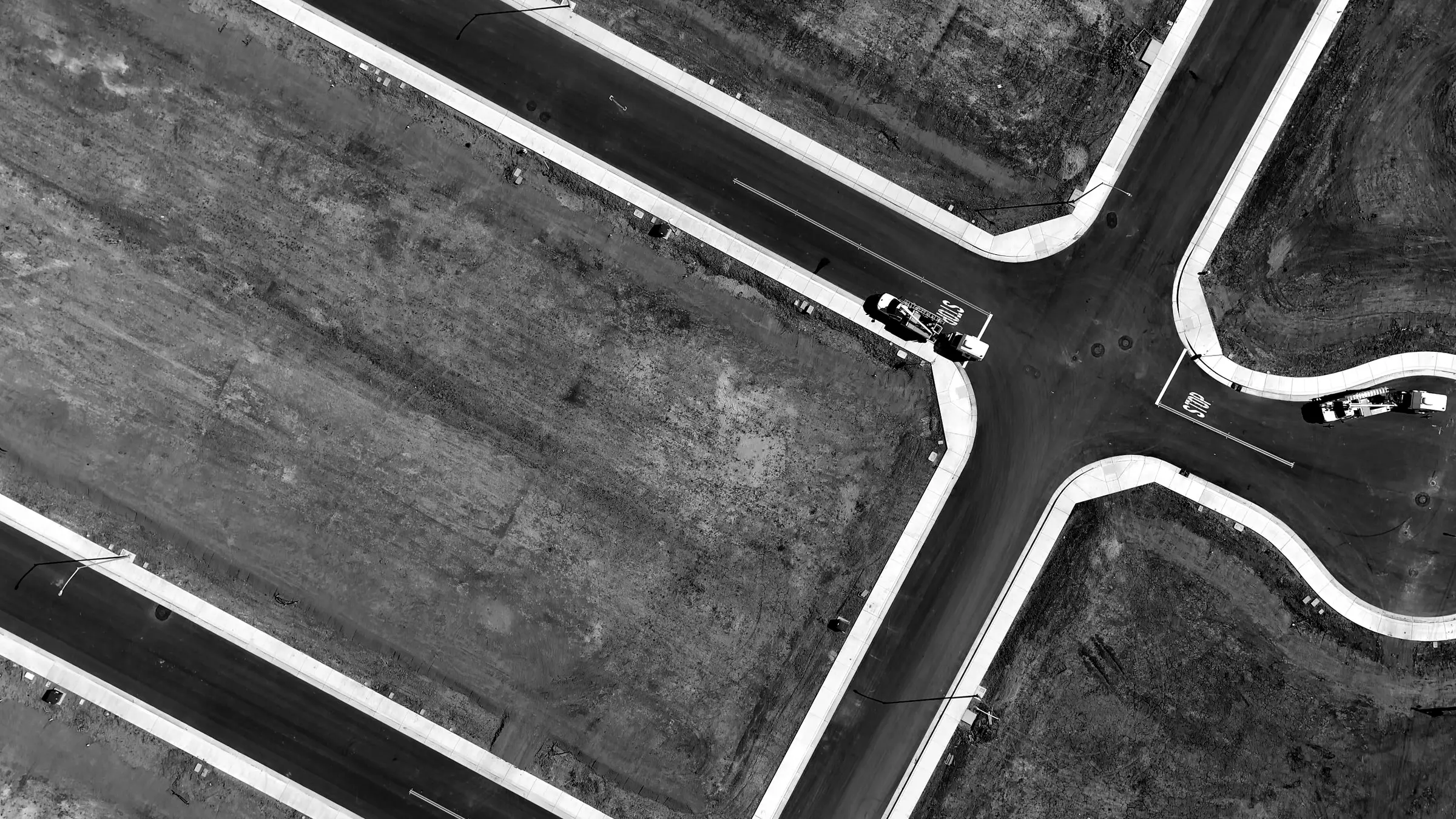 Aerial view of a new four-way road intersection between graded, empty commercial lots
